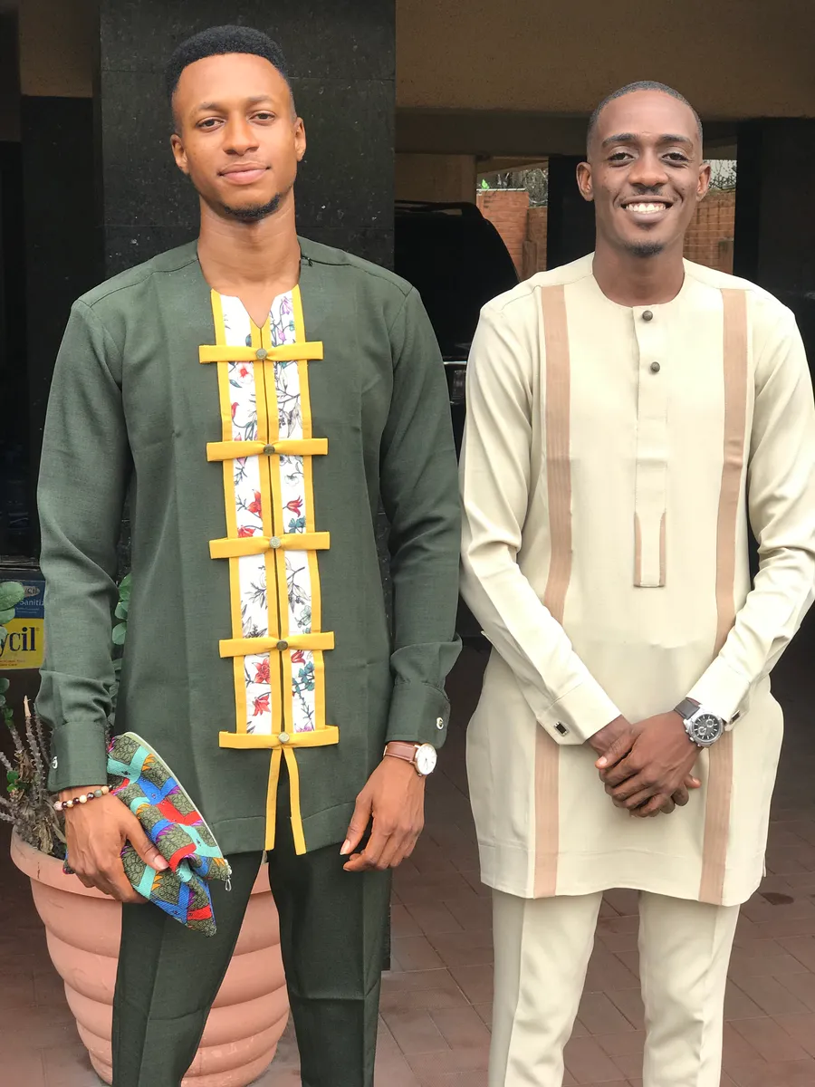 Two custom-fit natives worn side by side: a green two-piece with a yellow-framed floral panel down the front, and a cream two-piece with tan bands.
